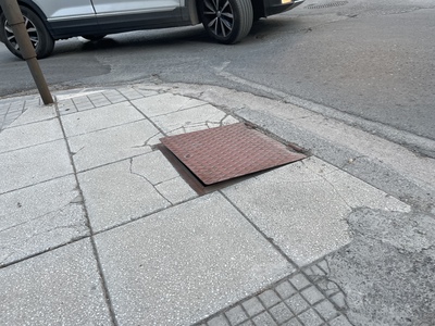 Χαλασμένο μεταλλικό καπάκι στο πεζοδρόμιο 